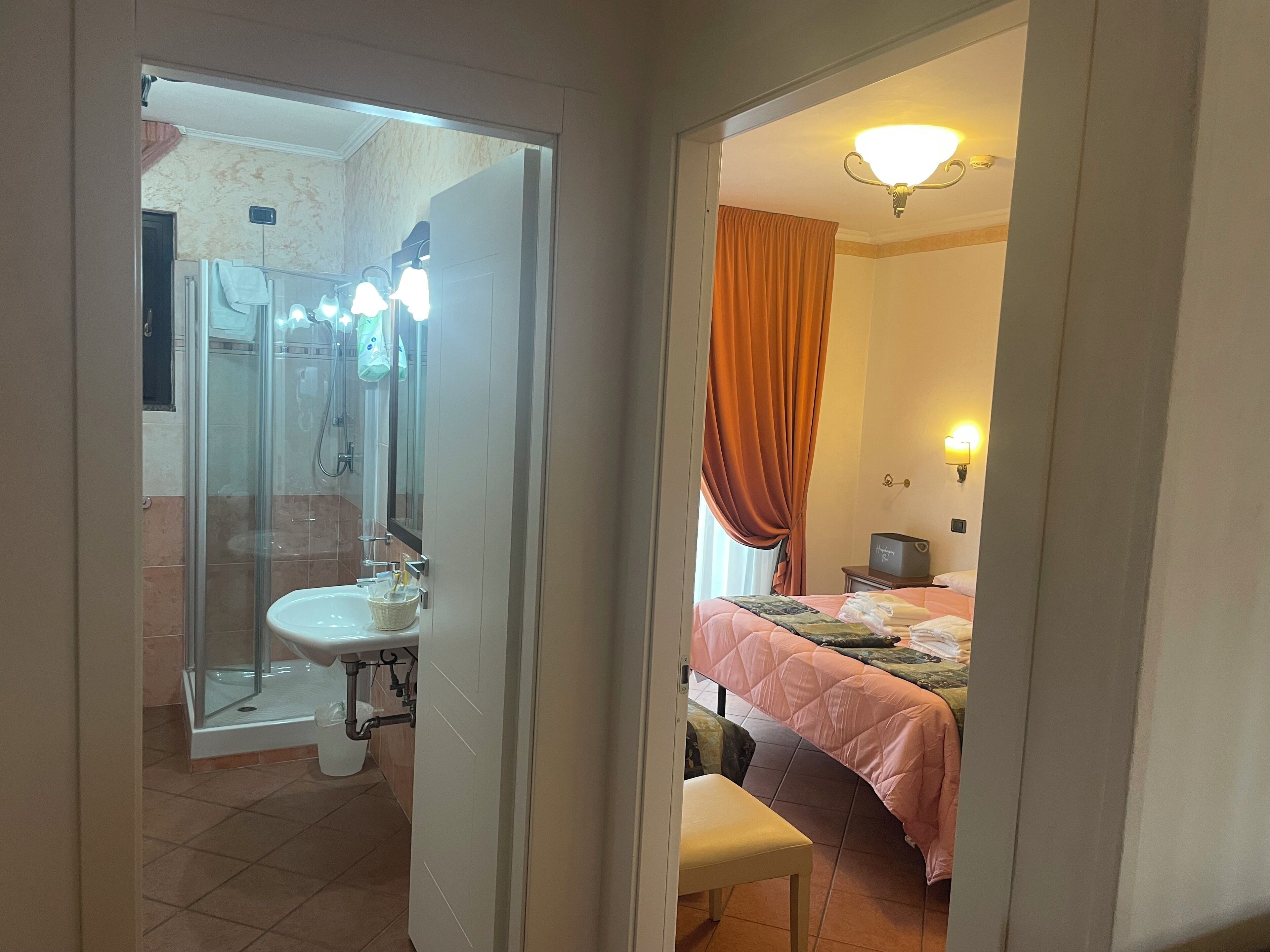 A bathroom with a glass shower enclosure, a sink, and a mirror.