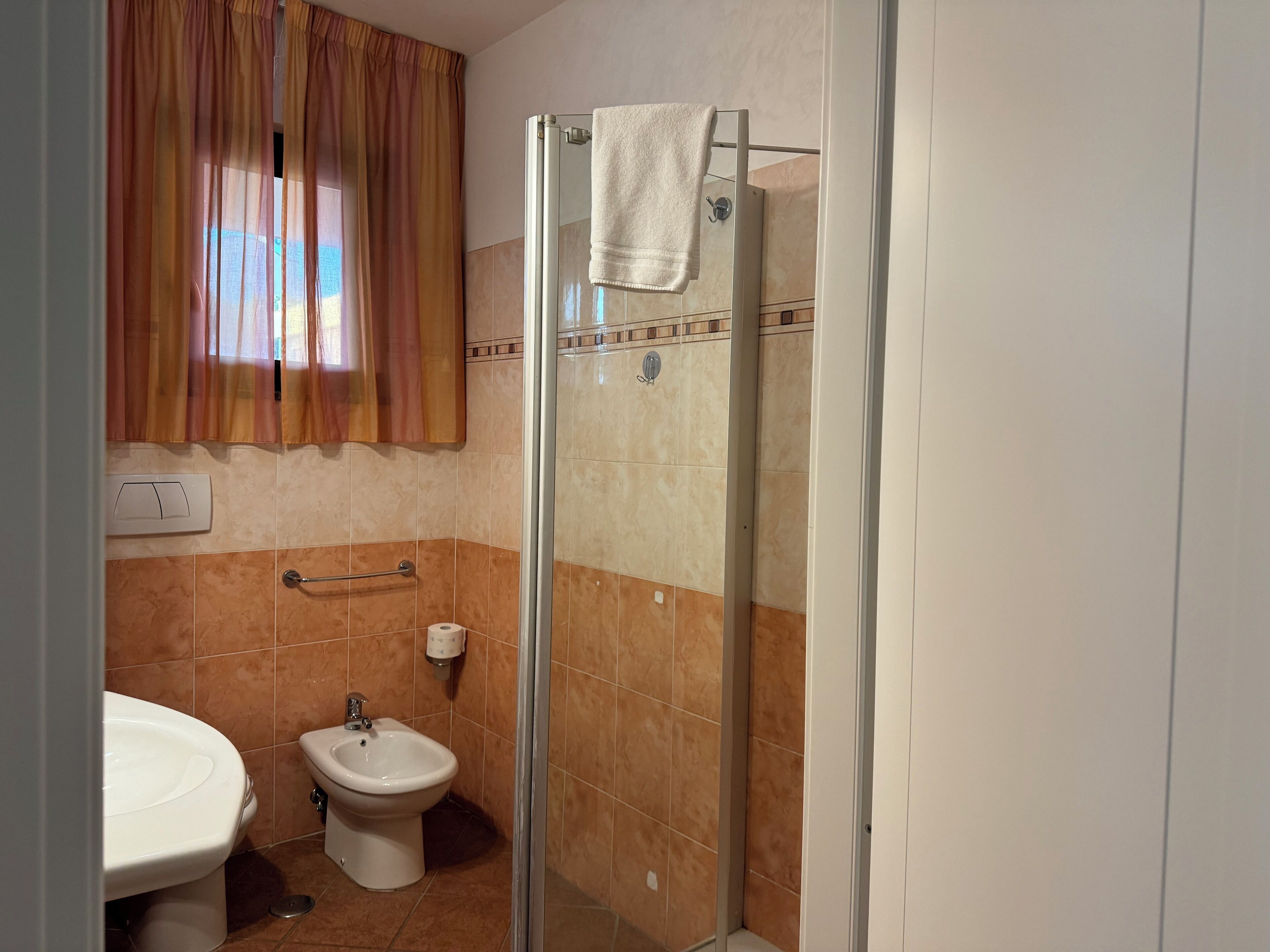 A bathroom with a glass shower enclosure, a bidet, and a toilet.