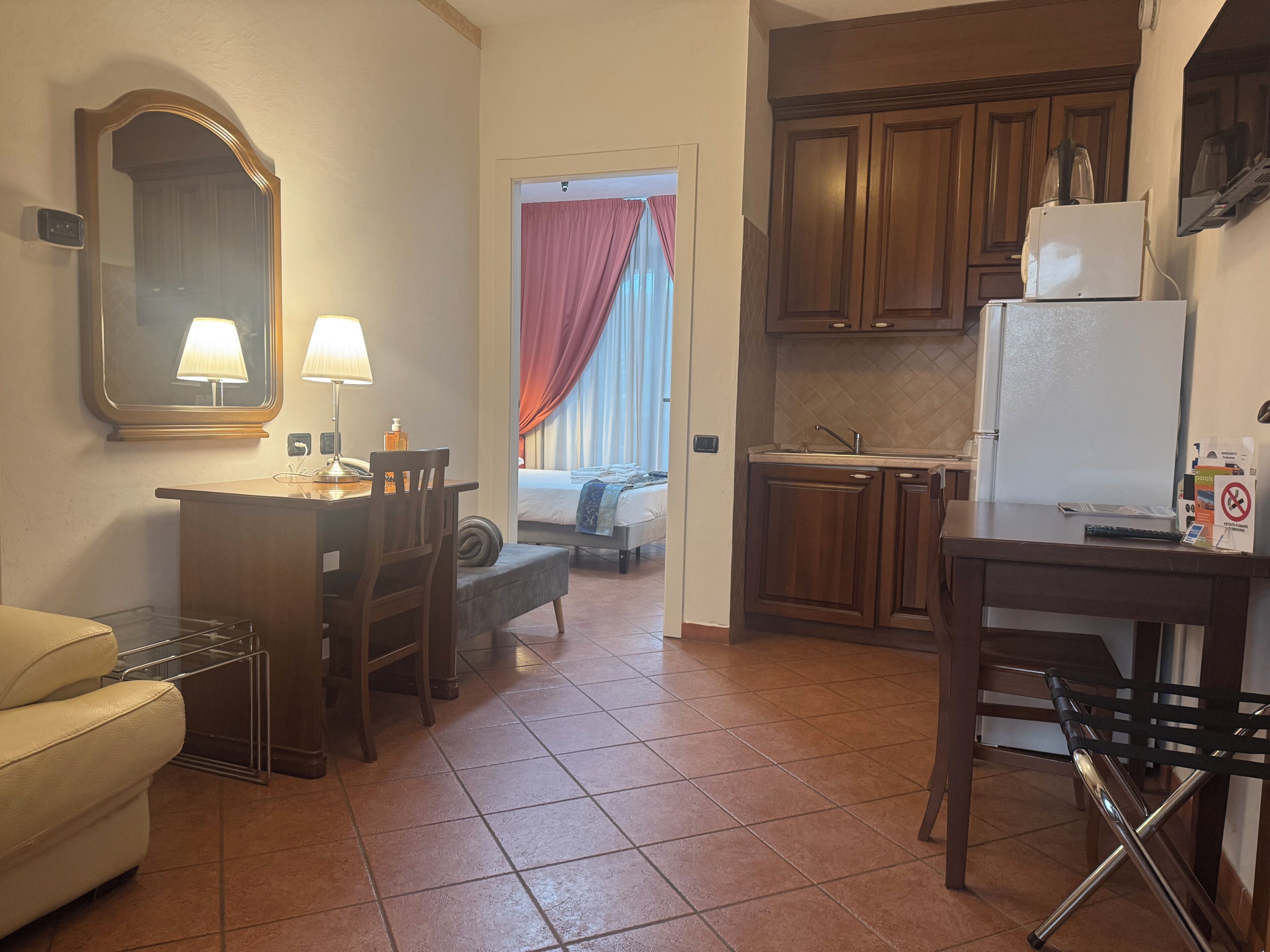 A compact hotel room with a kitchenette, a dining area, and a bed.