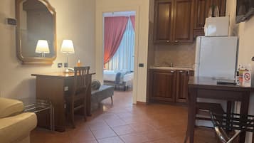 A compact hotel room with a kitchenette, a dining area, and a bed.
