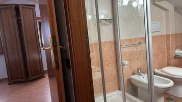 A bathroom with a glass-enclosed shower, a toilet, and a bidet.