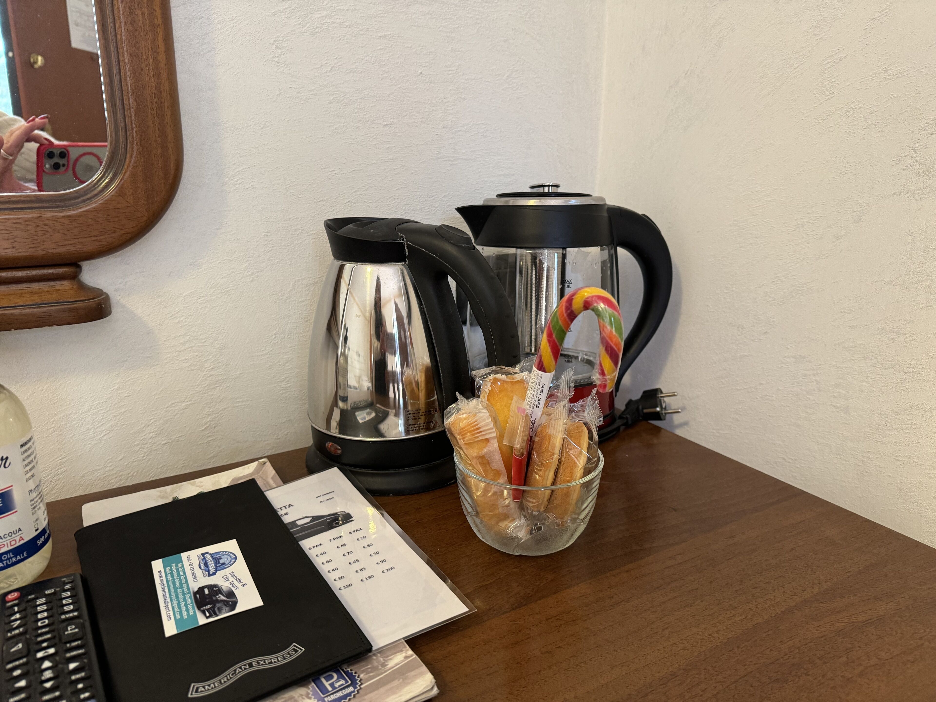 En köksbänk med en kaffebryggare, en vattenkokare, en glasskål med bröd, en flaska olja och en meny.
