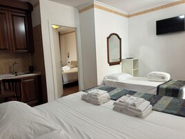 A hotel room with two beds, a sink, a mirror, and a television.
