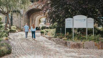 A cobblestone pathway leading to a stone building with a sign indicating a golf club and bar.