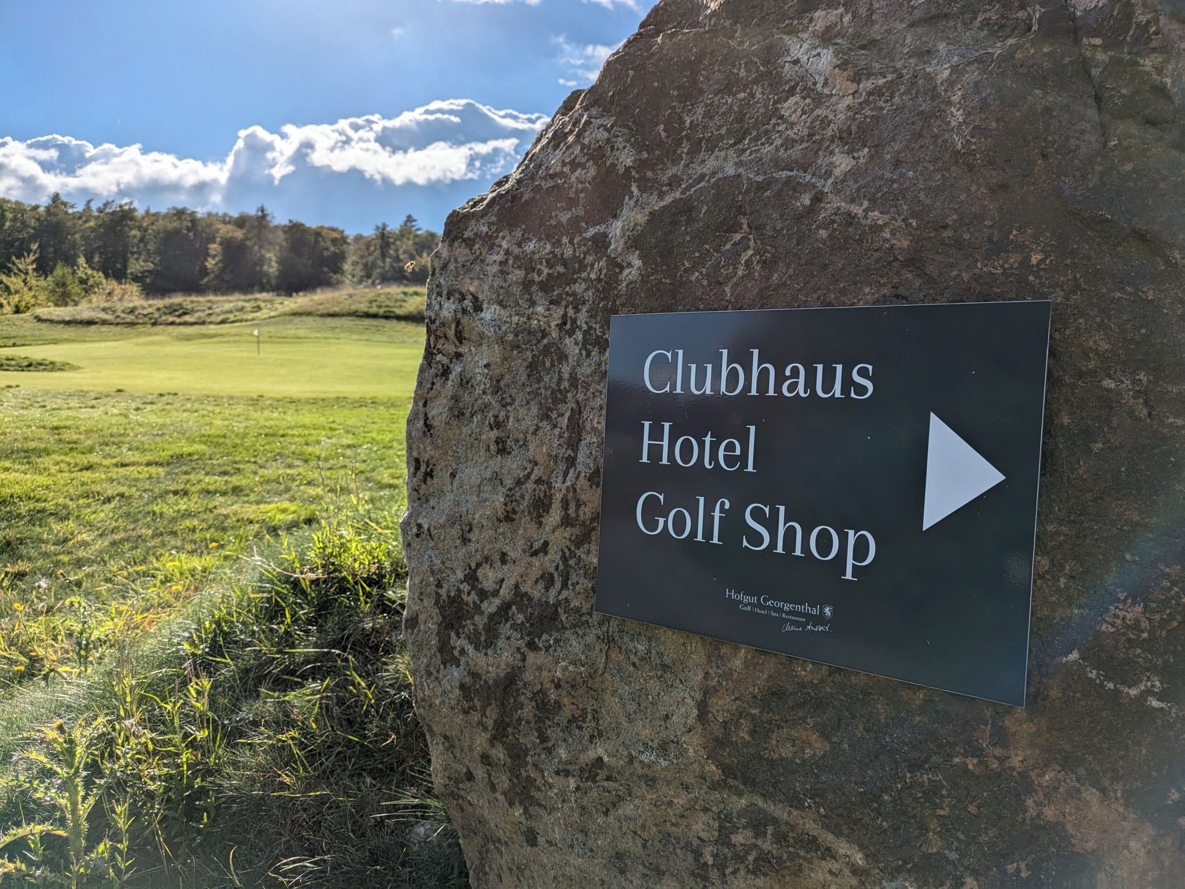 A sign for Clubhaus Hotel Golf Shop with a directional arrow.