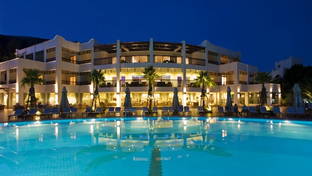 A hotel with a swimming pool, multiple balconies, and lounge areas with umbrellas. - Latanya Park Resort - All Inclusive (Bodrum)