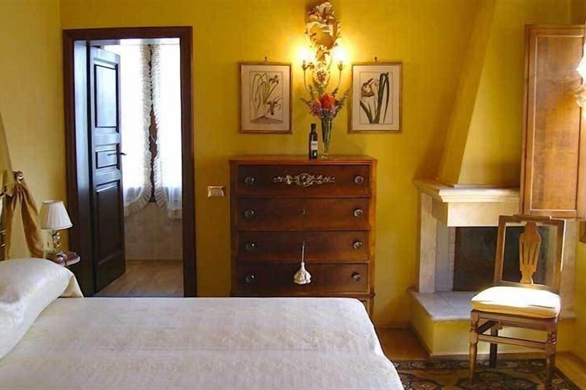 A hotel room with a bed, a wooden dresser, a chair, and two framed pictures on the wall.