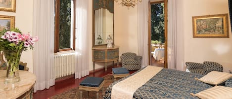 Un dormitorio con una cama grande, una zona de estar con una silla, un aparador y un espejo.