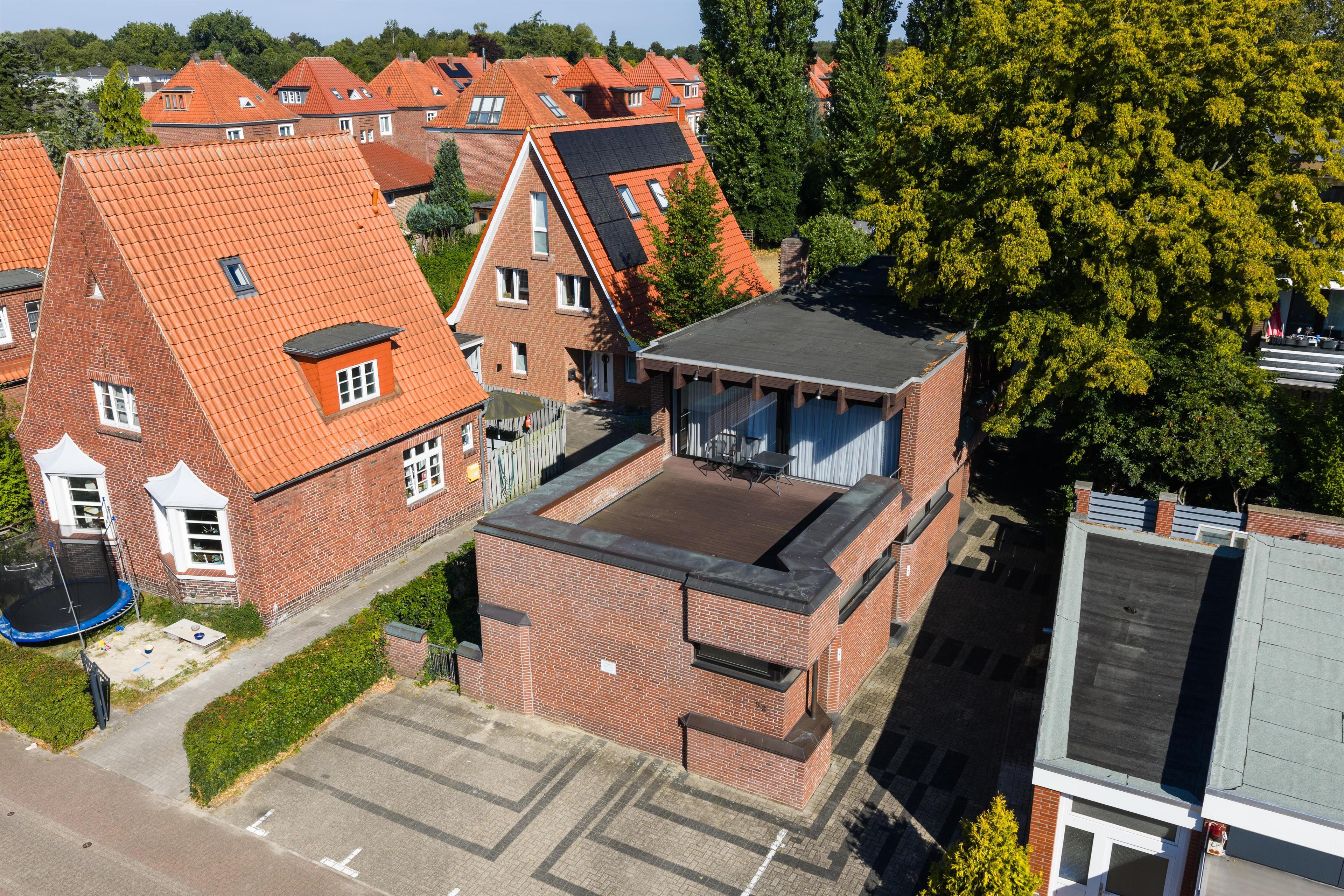 Een woonwijk met rode pannendaken, gebouwen van baksteen en een grote boom.