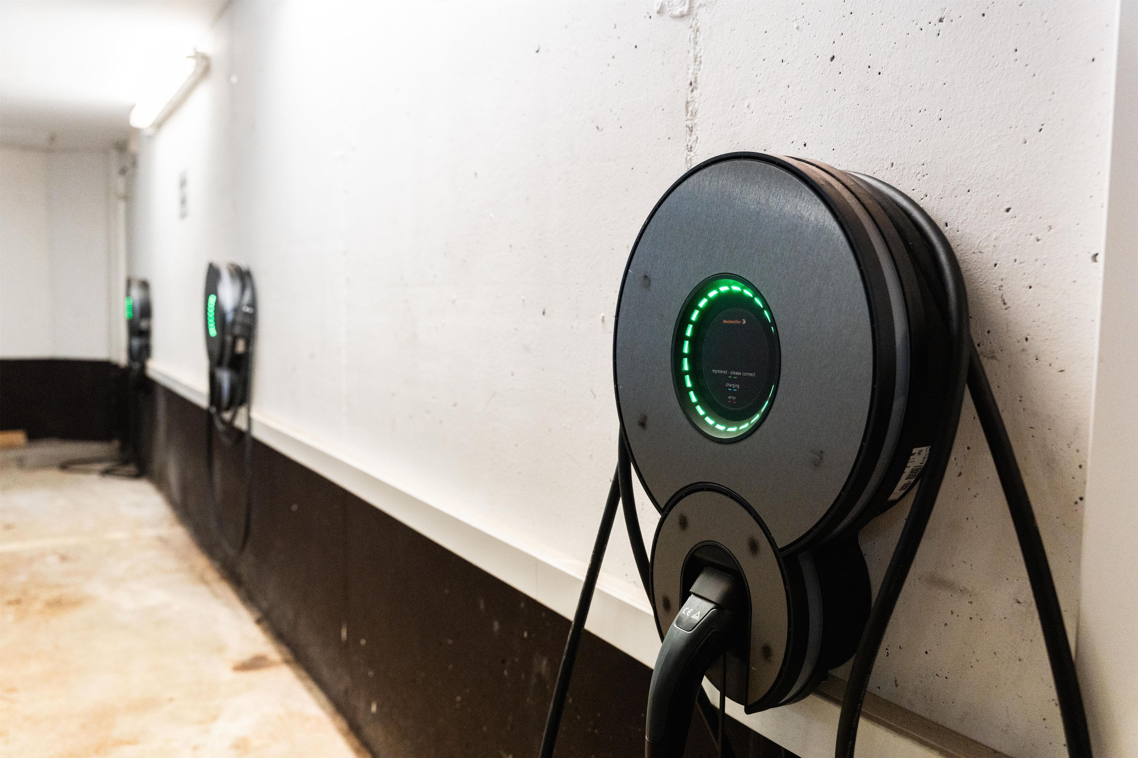 Una fila de estaciones de carga para vehículos eléctricos montadas en una pared en un pasillo.
