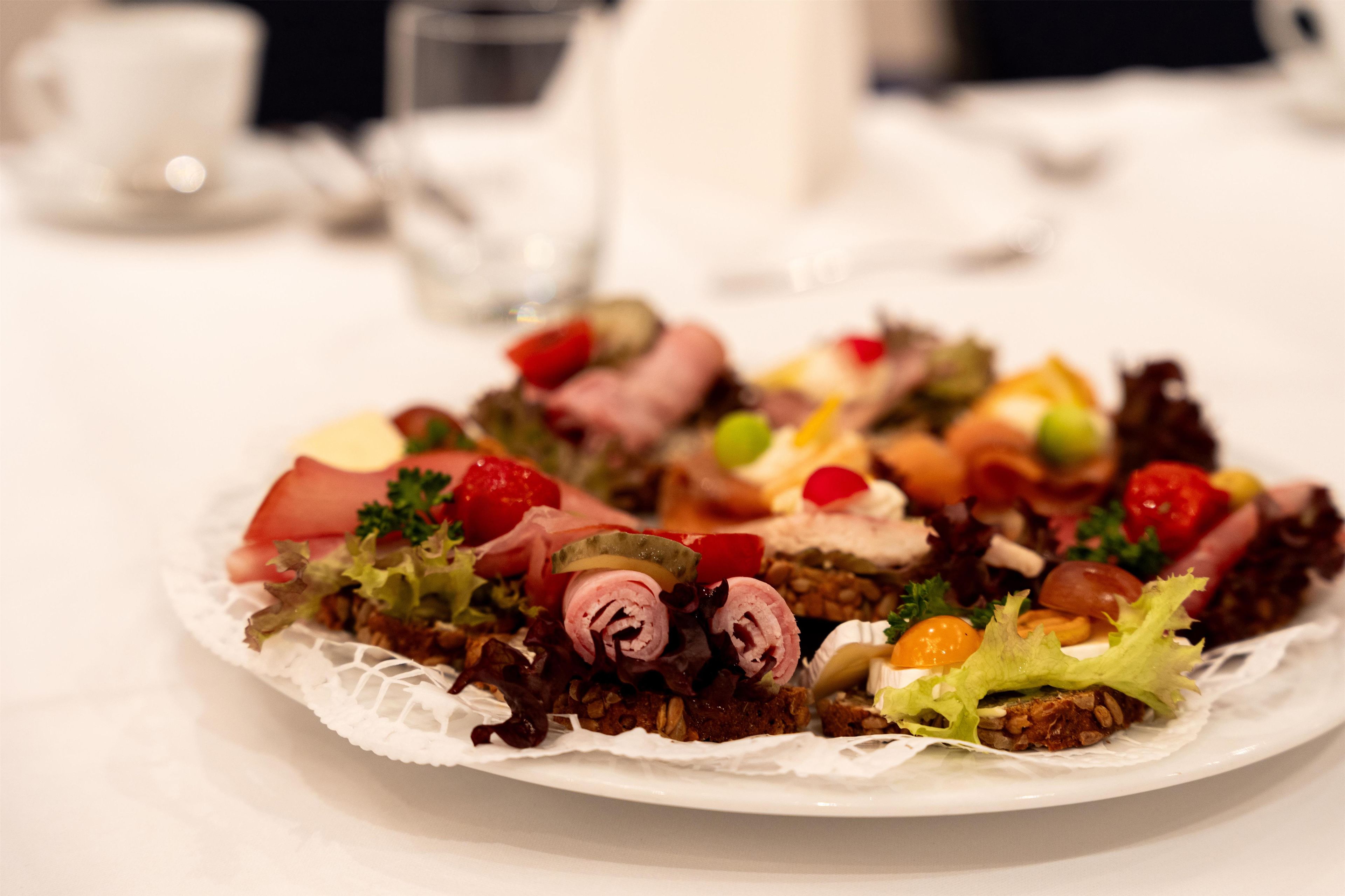 A plate of assorted food items including meats, vegetables, and possibly some fruit, arranged on a white plate with a lace doily underneath.