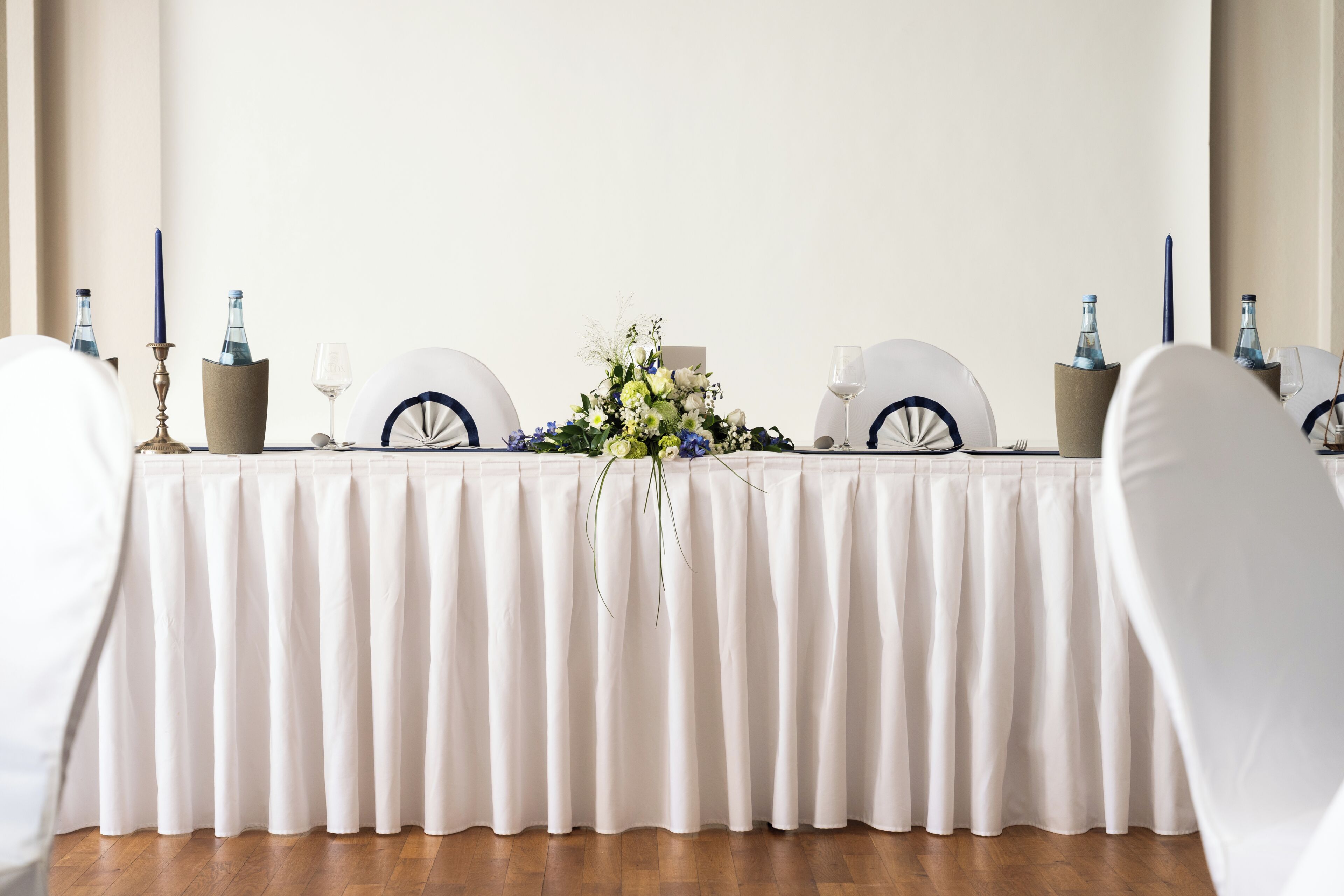 Taula ben a punt per a un esdeveniment formal, amb mantell blanc, vetreria i centrals florals.