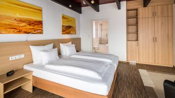Ein modernes Hotelzimmer mit einem Holzbett, weißen Bettwäsche, einem Holzschrank und zwei Landschaftsbildern an der Wand.
