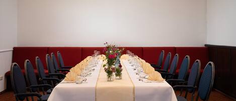 A conference room with a long table set for a meeting, surrounded by chairs.