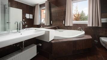 Une salle de bain moderne avec un double vasque, une baignoire et une fenêtre avec des rideaux.