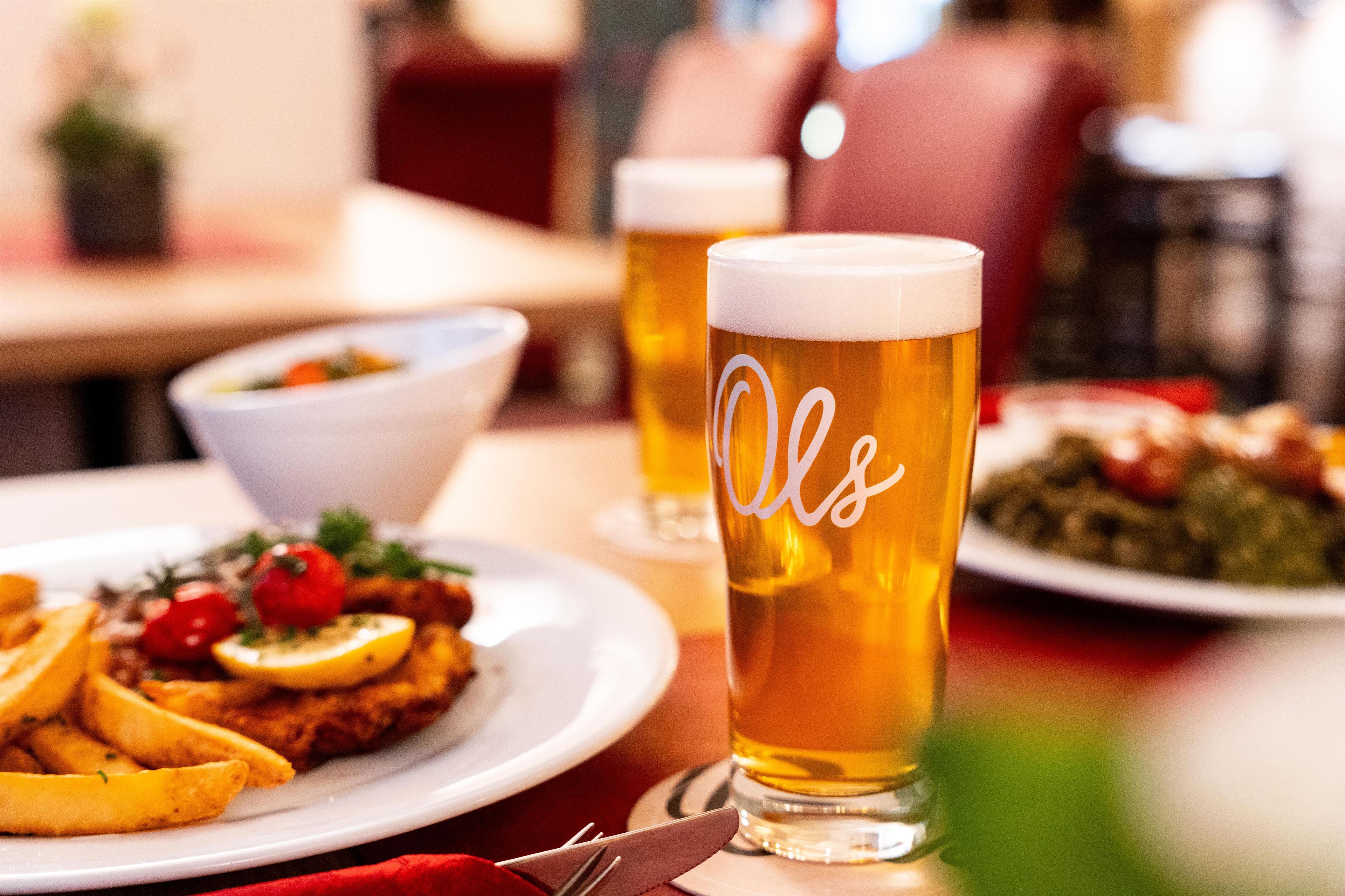 Una mesa de comedor con platos de comida y dos vasos de cerveza.