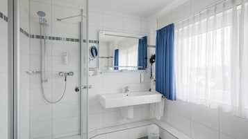A modern bathroom with a glass-enclosed shower, a white sink, and a large mirror.