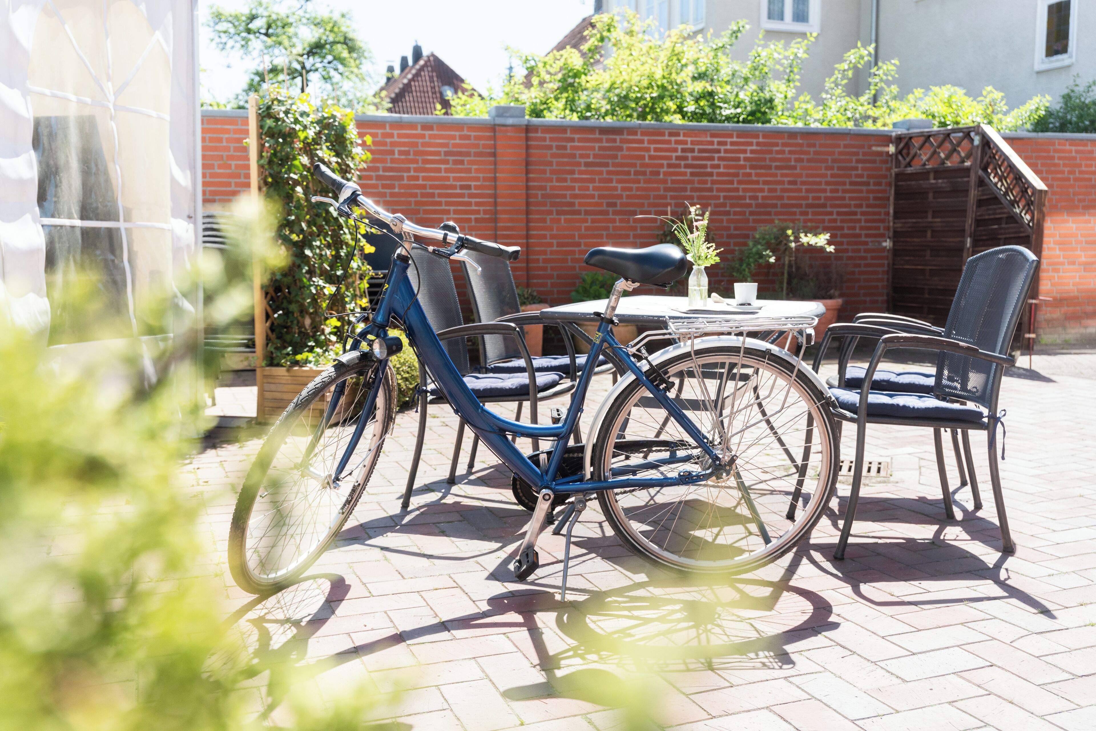 Une terrasse avec une table et des chaises, un vélo et un mur en briques.