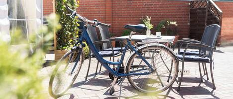 Un patio con una mesa, sillas, una bicicleta y un muro de ladrillo.