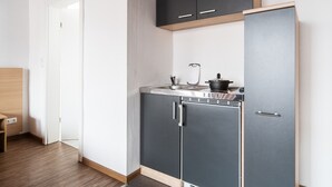 A compact kitchen with grey cabinets, a built-in oven, and a sink. - Best Western Hotel Heide (Oldenburg)