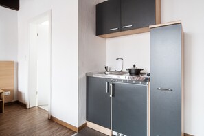A compact kitchen with grey cabinets, a built-in oven, and a sink. - Best Western Hotel Heide (Oldenburg)