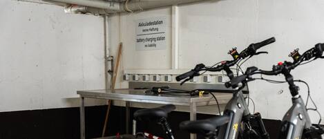 Una estación de carga para bicicletas con un letrero que indica que no se asume responsabilidad por la carga de la batería.