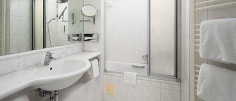 Un baño con lavamanos, espejo, ducha y toallero.