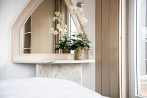 Un baño con lavamanos de mármol, un espejo y una planta en maceta con flores blancas.