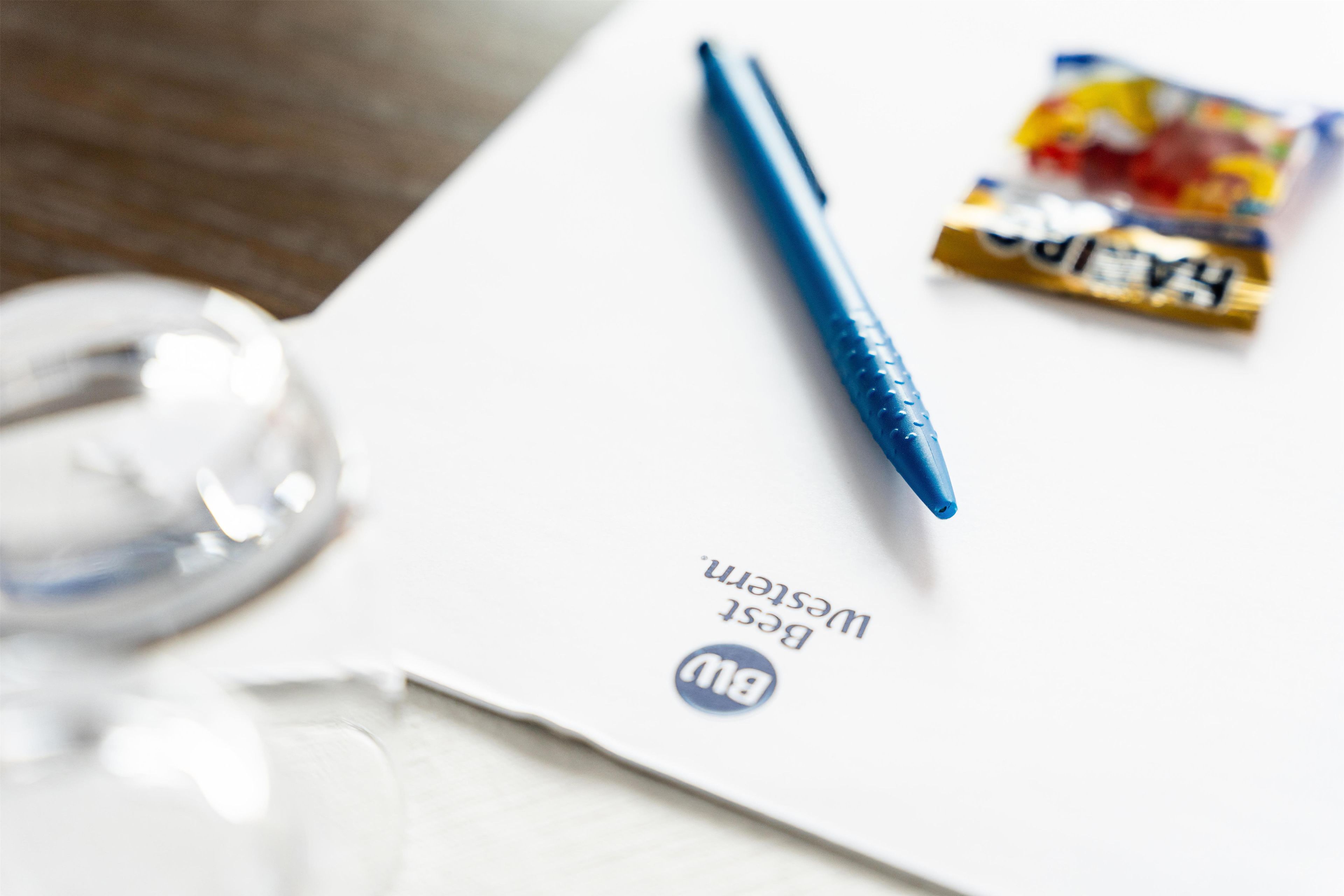 A white paper with a blue pen and a small packet of candy.