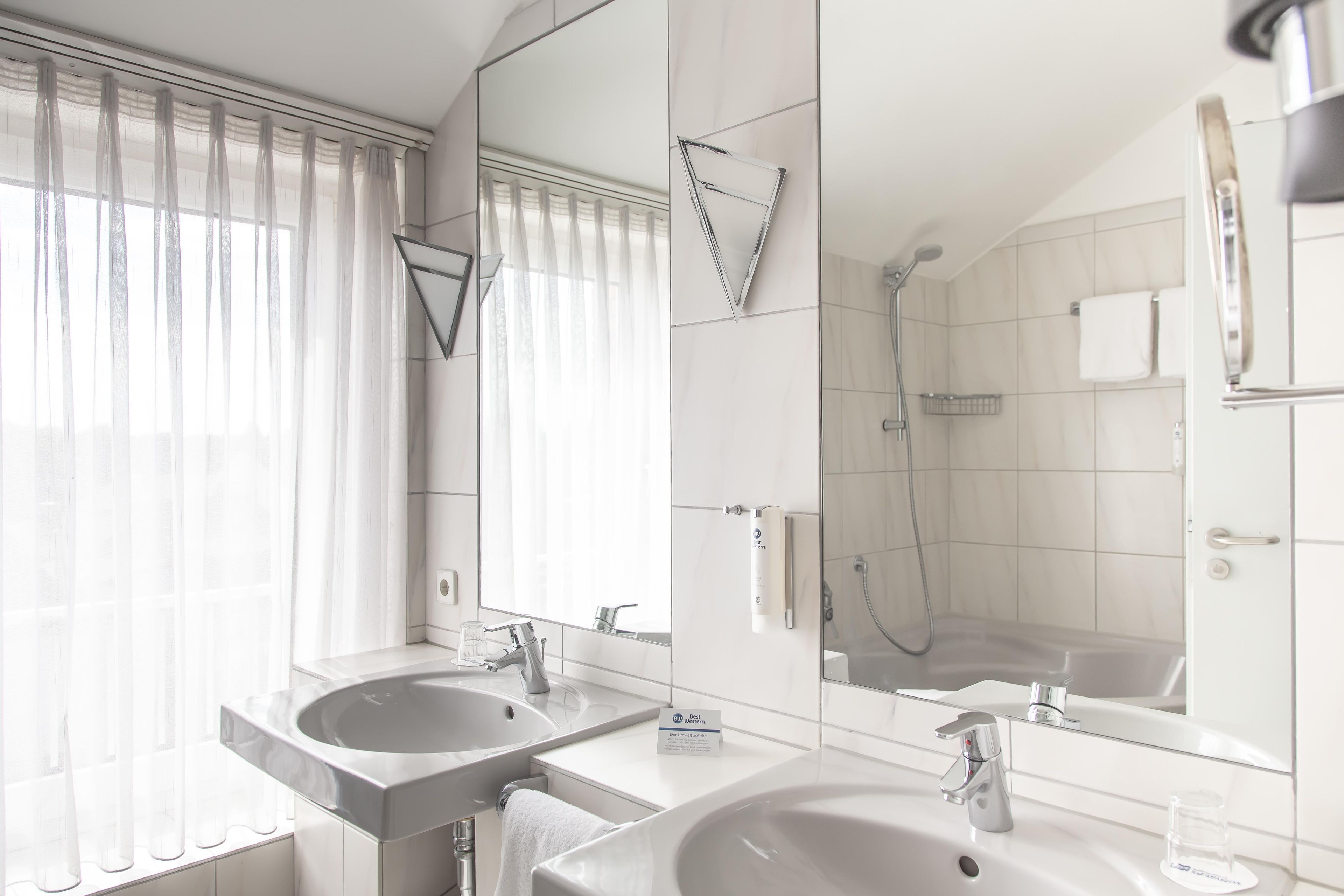 A modern bathroom with two sinks, a shower, and a large mirror.
