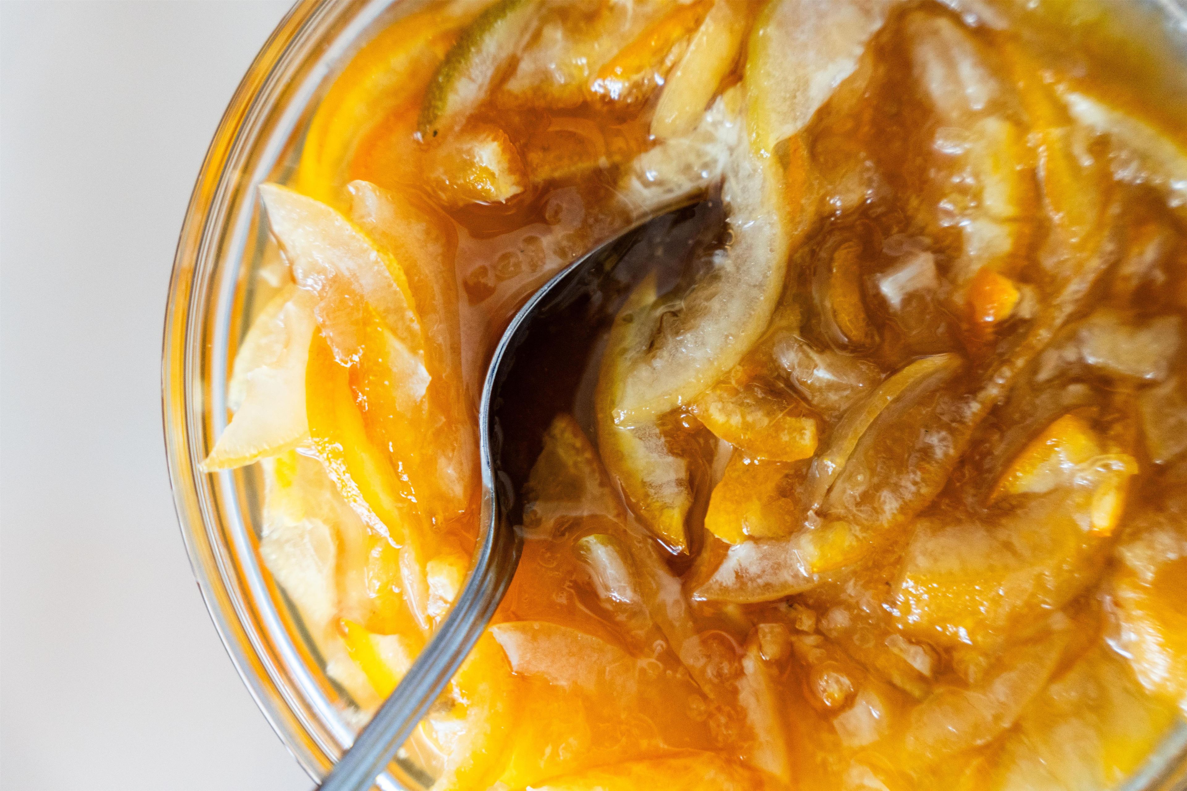 Une vue rapprochée d’un bol contenant une soupe translucide de couleur orangée, dans laquelle on distingue des morceaux, probablement des légumes ou des fruits.