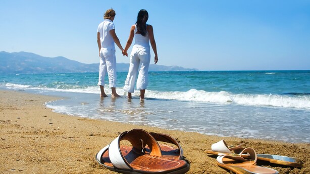 A beach with two people holding hands, a pair of sandals, and a hat on the sand. - Reutlingenhof Boutique Hotel - Special Class (Antalya)