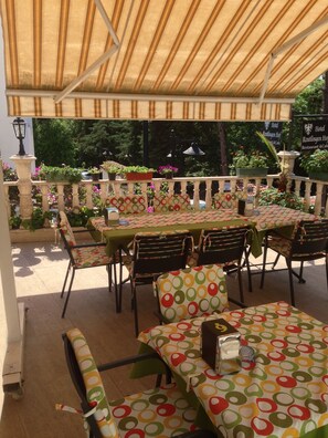 An outdoor patio area with tables and chairs covered in polka dot tablecloths, a decorative lamp post, and signs for a hotel and restaurant. - Reutlingenhof Boutique Hotel - Special Class (Antalya)
