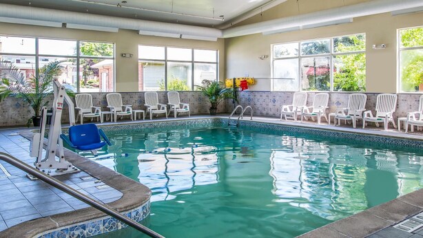 Une piscine intérieure à l’eau claire, dotée de chaises longues blanches et d’un poste de surveillance pour les sauveteurs.