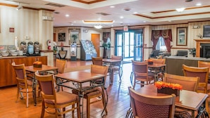 Un hall d’hôtel avec un plancher en bois, un comptoir de réception et plusieurs tables et chaises.