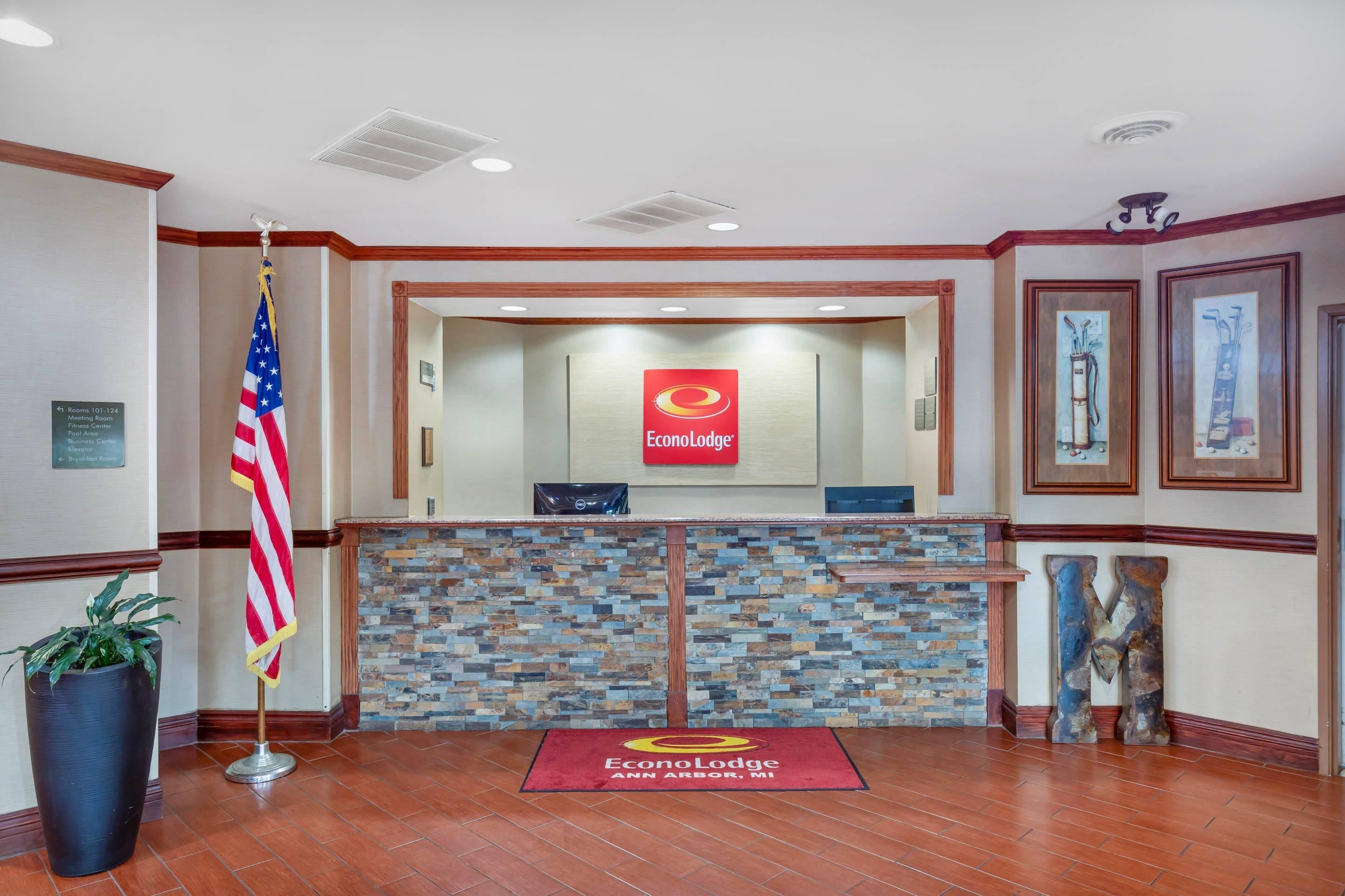 Un área de recepción con pared de piedra, alfombra roja y una bandera.