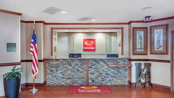 Un área de recepción con pared de piedra, alfombra roja y una bandera.