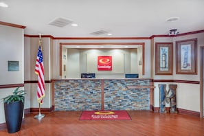 Un área de recepción con pared de piedra, alfombra roja y una bandera.