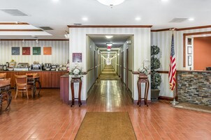 Un vestíbulo de hotel con un largo pasillo, área de recepción y una estación de café.