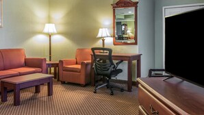 A hotel room with a sofa, two armchairs, a desk, a chair, a television, and two lamps. - Quality Inn & Suites Ann Arbor Hwy 23 (Ann Arbor)