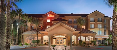 A hotel with a prominent entrance, multiple balconies, and a well-lit facade.