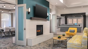 Een moderne woonkamer met een open haard, een flatscreen-tv, een gele fauteuil en een gele bank.