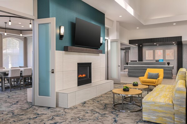 Un salón moderno con chimenea, un televisor de pantalla plana, un sillón amarillo y un sofá amarillo.
