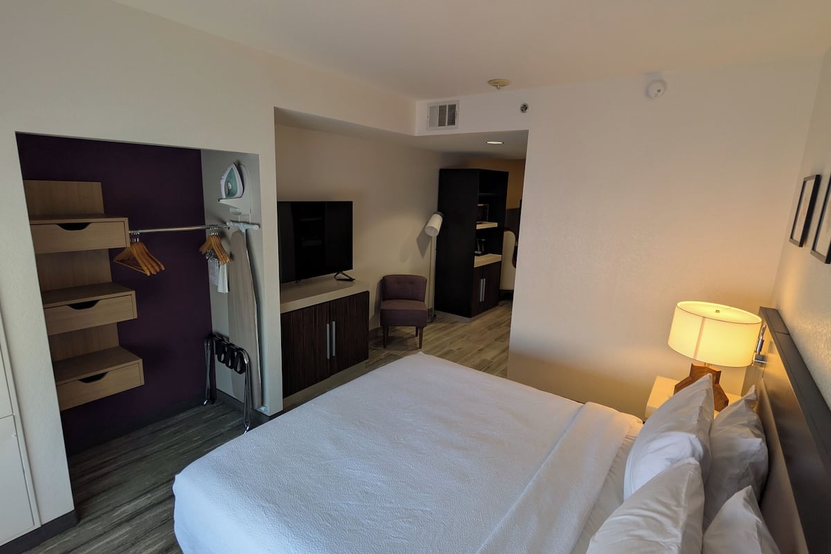 A hotel room with a large bed, a TV, a desk, and a chair.