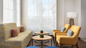 A modern lounge area with a sofa, two armchairs, a small table with potted plants, and a floor lamp. - Hilton Garden Inn Las Vegas Strip South (Las Vegas)