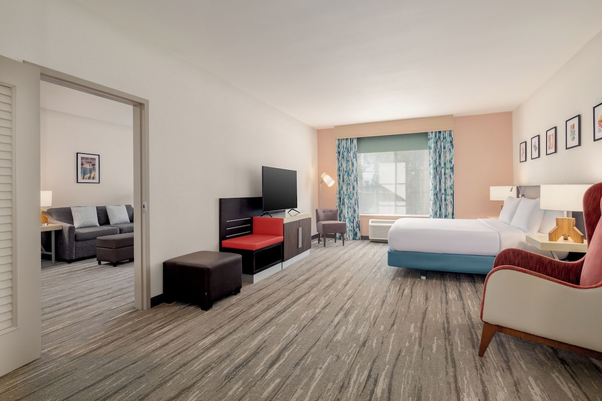 A hotel room with a bed, a TV, a desk, a sofa, and a chair.