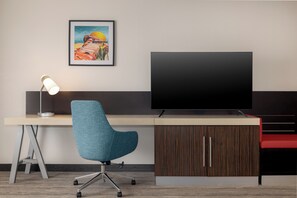 Un escritorio moderno con una silla giratoria, un televisor de pantalla plana y un cuadro en la pared.