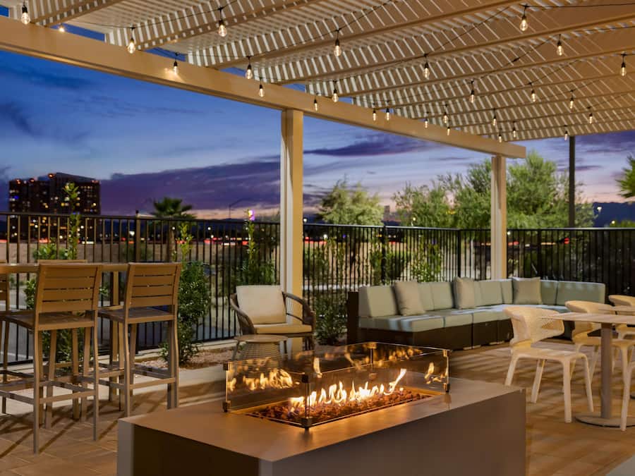 Un patio al aire libre con una fogata, asientos y vistas a la ciudad al anochecer.