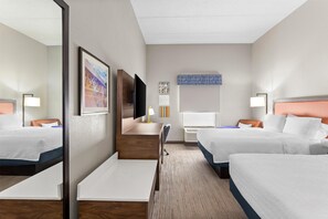 A hotel room with two beds, a desk, a chair, a TV, and a mirror.