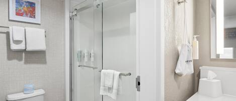 A modern bathroom with a glass shower enclosure, a toilet, and a sink with a mirror.